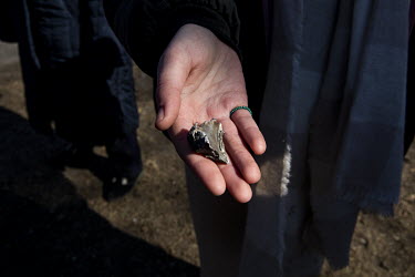 Sasha Myhova holds a piece of shrapnel from a Russian shell that she said had landed in the yard of their home in Irpin.