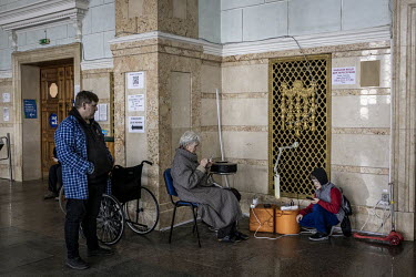 People who have fled their homes in various parts of Ukraine charging their mobile phones while they wait in a reception area at Kyiv central station before travelling onward.