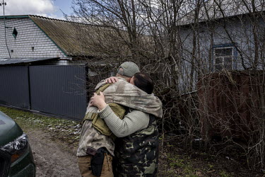 A member of the Territorial Defence Forces embraces a resident of the village that was retaken from invading Russian forces on 31 March 2022.