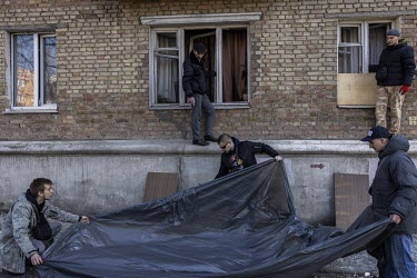 Local residents and volunteers work to clean up debris and repair windows at an apartment block, after it was struck in a Russian multiple rocket attack in the Nyvky district of western Kyiv early tha...