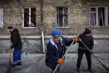 Local residents and volunteers work to clean up debris and repair windows at an apartment block, after it was struck in a Russian multiple rocket attack in the Nyvky district of western Kyiv early tha...