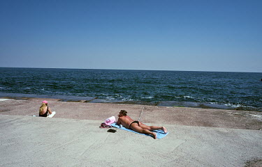 A woman sunbathing on Lanzheron Beach promenade despite Russia's war.