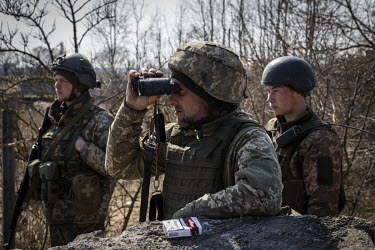 Ukrainian soldiers scan the horizon at a checkpoint on a frontline position in the northern region of Kyiv.