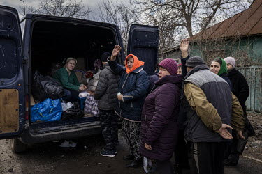 Women queuing for food aid wave to passing Ukrainian soldiers in the recently liberated village of Nova Basan.