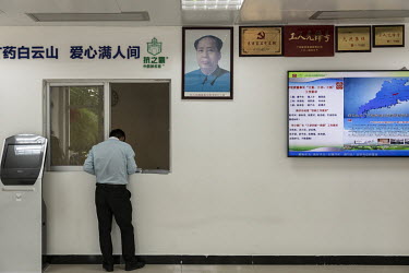 An employee checks in while standing under a portrait of Chairman Mao at Guangzhou Pharmaceutical Holdings Ltd.'s Baiyunshan plant.