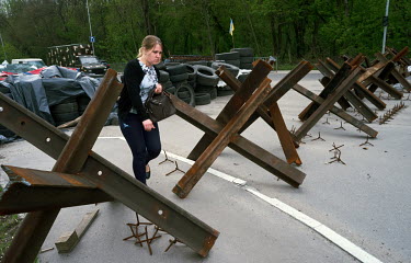 A woman walks past Czech hedgehogs, an anti-tank structures that block the street.
