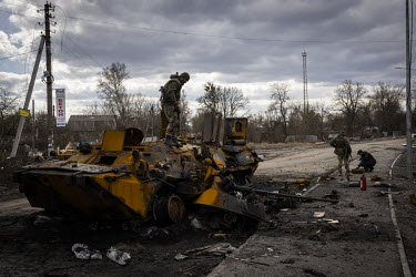 Volunteer fighters search a destroyed Russian armoured fighting vehicle for anything salvageable in the village of Nova Basan.