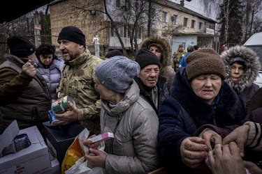 People crowd around a pick-up truck distributing aid in the recently liberated but heavily destroyed town of Borodyanko.