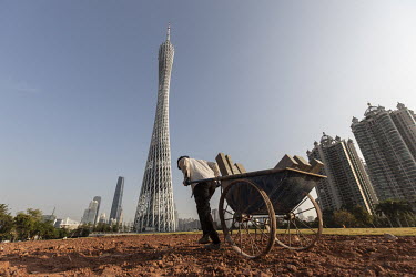 A groundskeeper pulls a cart loads with building materials near the Canton Tower.