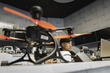 A drone sits on a desk as employees work in front of computers in a testing facility at the EHang Inc. headquarters. The Chinese startup has developed a flying car that it plans to roll out as soon as...