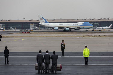 Attendants wait to roll out the red carpet as U.S. president Donald Trump's Airforce One taxis on a runway at the Beijing Capitol Airport.