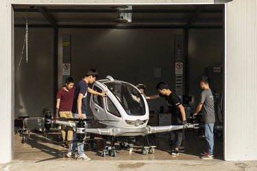 Employees move an EHang Inc. E-184 drone out of storage ahead of a test flight at the testing facility at the EHang Inc. headquarters. The Chinese startup has developed a flying car that it plans to r...