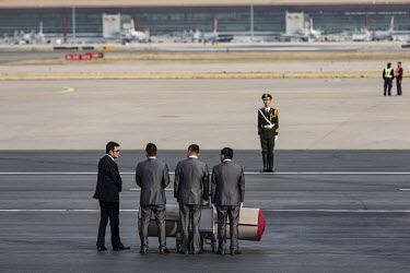 Attendants wait to roll out the red carpet as U.S. president Donald Trump's Airforce One approaches the Beijing Capitol Airport.