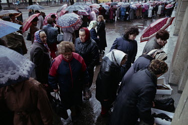 People queue in the rain to buy shoes.
