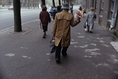 A man carrying a piece of meat home through the streets.