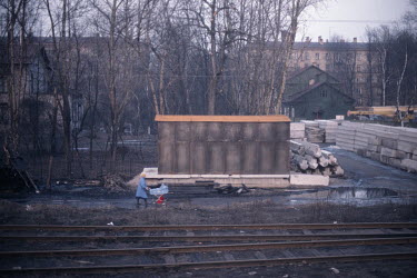 A woman pushing a pram in a small town seen through the window of a train travelling from Helsinki to Leningrad.