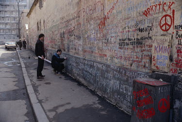 A man adds to the political graffiti on a wall on a Moscow street.