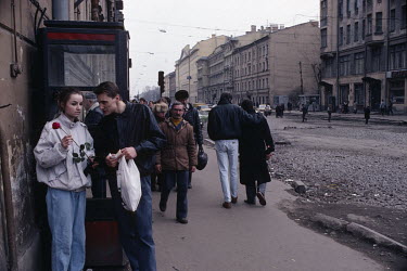 A young couple talk beside a public phone booth on a street in the city where the road has been dug up.
