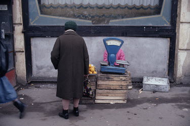 A woman stops beside a pavement stall selling oranages