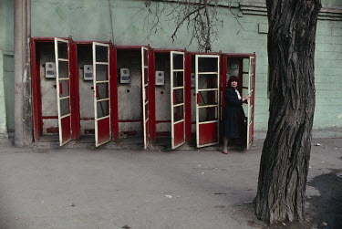 A woman exits a phone booth.
