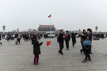A woman takes a photograph of a girl in Tiananmen Square.
