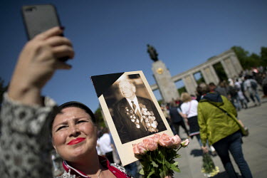 A Russian woman with a picture of a Russian soldier and relative who fought in the Soviet army in World War II during a rally to commemorate the sacrifices of the Soviet Red Army on the 77th anniversa...