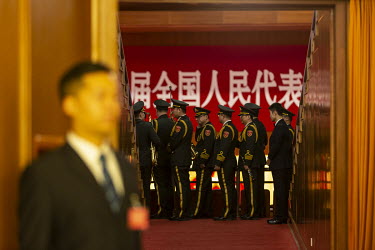 An attendant stands at the entrance of the auditorium at the Great Hall of the People as a military band files past before the opening of the first session of the 13th National People's Congress (NPC)...