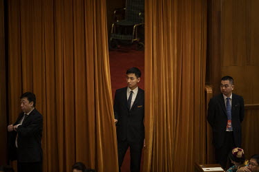 An attendant looks out from behind a curtain at the 13th National People's Congress (NPC) at the Great Hall of the People.