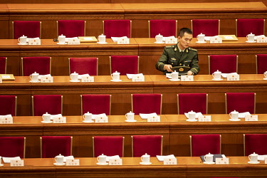 A military officer seats himself before the opening of the first session of the 13th National People's Congress (NPC) at the Great Hall of the People.
