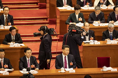 Cameramen walk behind Xi Jinping, China's president, as he listens during a speech at the opening of the first session of the 13th National People's Congress (NPC) at the Great Hall of the People.
