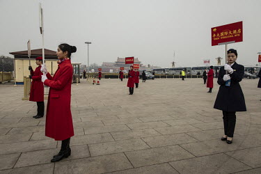 Attendants hold up sign to direct delegates to their transportation while standing on Tiananmen Square after the opening of the first session of the 13th Chinese People's Political Consultative Confer...