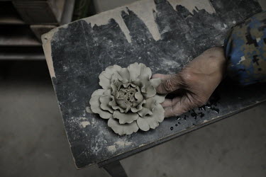 A worker with a clay flower inside a workshop at the Jingdezhen Porcelain Factory.