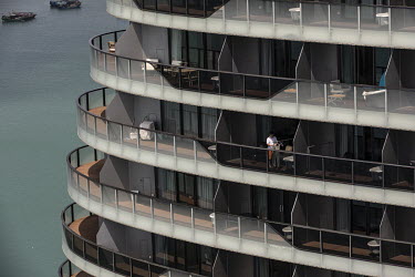 A man stands on the balcony of a residential building on Phoenix Island, an artificial archipelago developed by Sanya Phoenix Island Development Co.