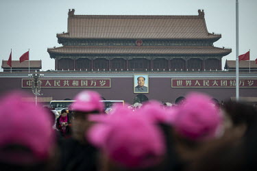 A portrait of Chairman Mao hangs over tourists walking through Tiananmen Square.