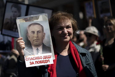 A Russian woman with a photo of a Russian soldier and relative who fought in the Soviet army and died in World War II during a rally to commemorate the sacrifices of the Soviet Red Army on the 77th an...