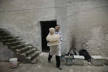 A worker carries a bust of former Chinese leader Mao Zedong through a workshop at the Jingdezhen Porcelain Factory.