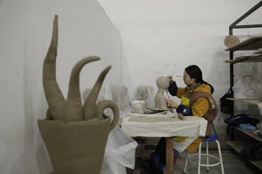 A crafts person working on a clay bust inside a workshop at the Jingdezhen Porcelain Factory.