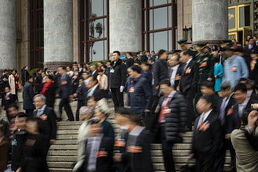 Delegates walk out of the Great Hall of the People past an attendant after the the opening of the first session of the 13th National People's Congress (NPC).