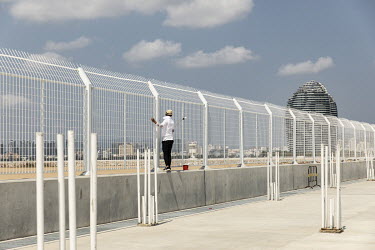 A worker paints a fence at the construction site for Phase II of Phoenix Island, an artificial archipelago developed by Sanya Phoenix Island Development Co.