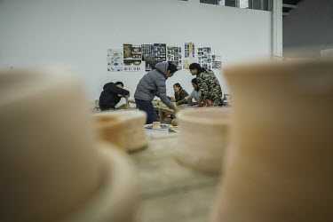 Crafts people making clay items in a workshop at the Jingdezhen Porcelain Factory.