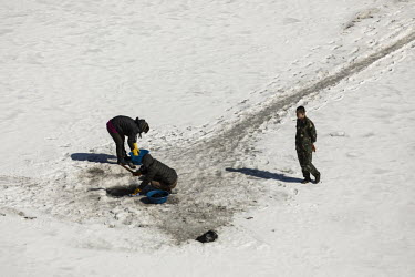 A soldier, stands and looks on as women wash clothes through a hole broken through the frozen Yalu River in Hyesan, North Korea, seen from across the border in Changbai.