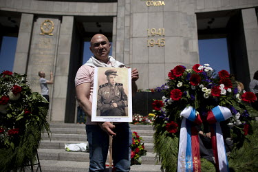 A Russian man with a picture of a Russian soldier and relative who fought in the Soviet army in World War II during a rally to commemorate the sacrifices of the Soviet Red Army on the 77th anniversary...
