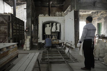 A worker pushes a cart loaded with busts of former Chinese leader Mao Zedong into a furnace for firing at a workshop at the Jingdezhen Porcelain Factory.
