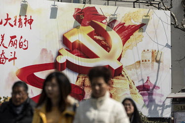 Pedestrians walk past a propaganda poster for the Chinese Communist Party.