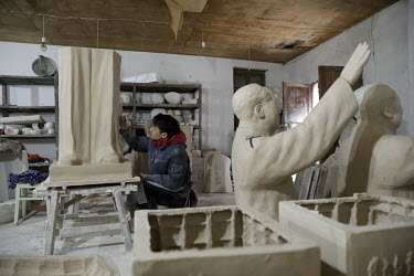 A worker sculpts the legs of former Chinese leader Mao Zedong inside a workshop at the Jingdezhen Porcelain Factory