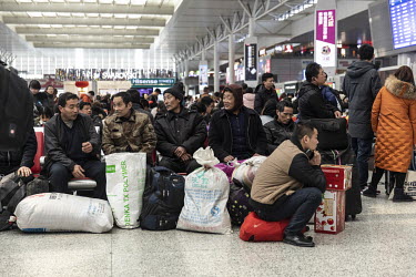 Migrant workers sit with their belonging in the main hall of the Shanghai Hongqiao Railway Station.