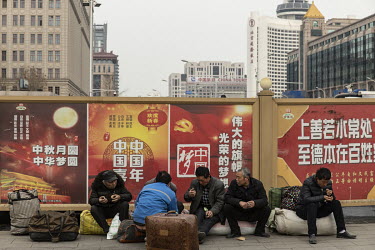 Passengers sit on their belongings while waiting for their train outside of the old Beijing railway station.