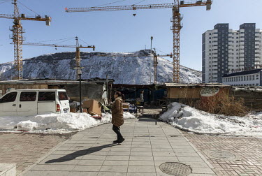 A woman walks past construction cranes in the town of Changbai on China's border with North Korea.