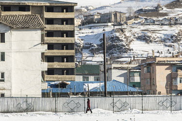 A woman walks on the North Korean side of the border fence in the town of Hyesan, seen from across the border in Changbai.