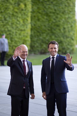 Olaf Scholz, Chancellor of Germany (SPD), and Emmanuel Macron, President of France wave to press at the Chancellery Office.